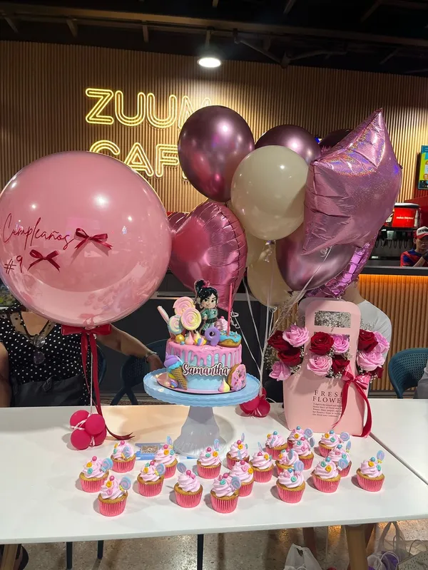 Decoración de cumpleaños con torta, cupcakes y globos en el Zuum Café