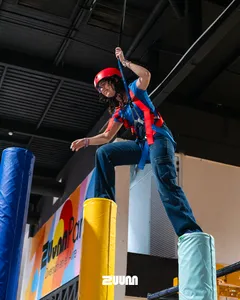 Visitante con casco rojo y arnés superando un obstáculo en la Torre Zuum de Zuum Park