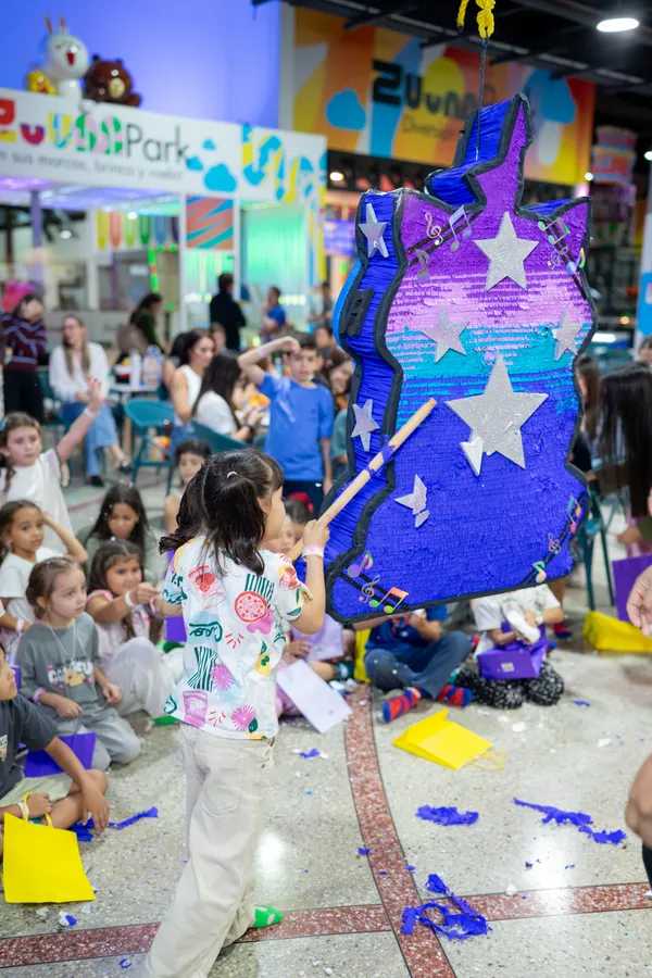 Niña golpeando una piñata durante la celebración del Plan Vuela en Zuum Park